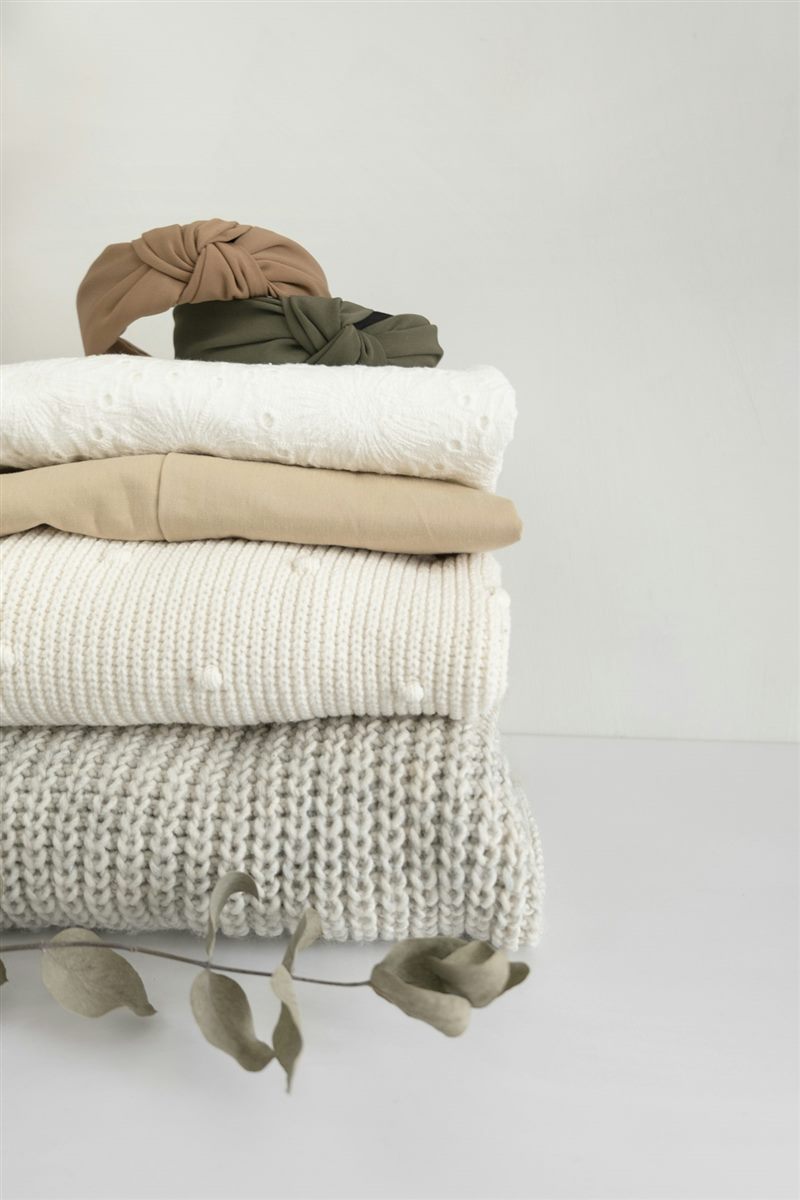 Stack of folded knits and sweatshirts in cream and sand